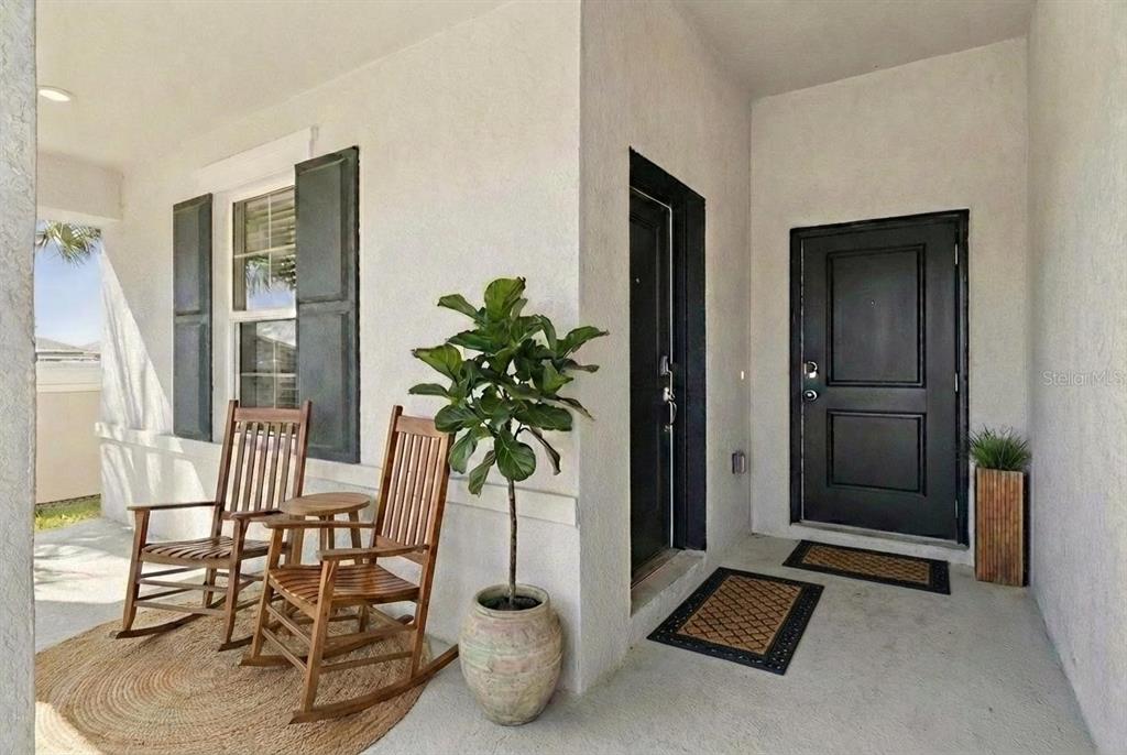 A covered porch features two wooden rocking chairs, a potted plant, and two black doors — 101 KAYAK AVENUE, HAINES CITY, FL