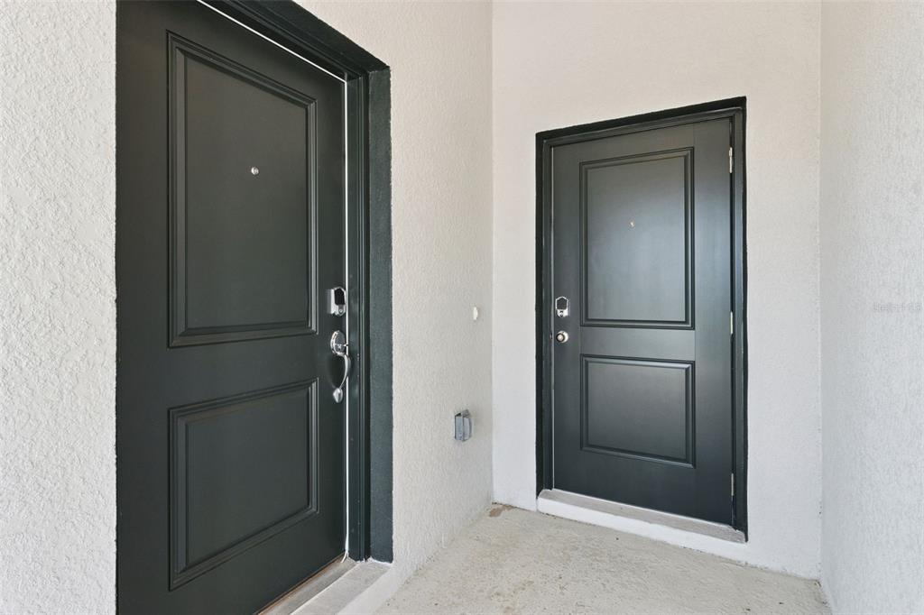Two black doors with silver hardware are set into a white stucco entryway — 101 KAYAK AVENUE, HAINES CITY, FL