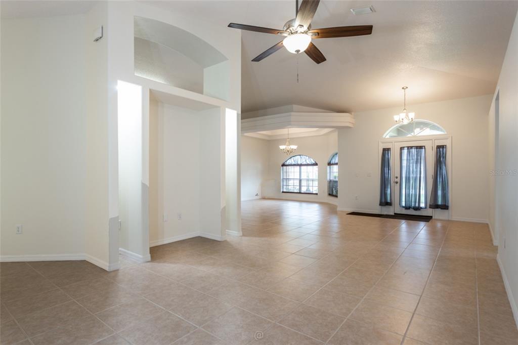 A spacious living area features tile flooring, a vaulted ceiling with a fan, and arched windows — 3 ZODIAC PLACE, PALM COAST, FL