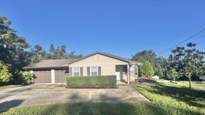 A single-story house with a concrete driveway, a two-car garage, and a manicured front hedge — 1340 ANDERSON STREET UNIT 1350, CLERMONT, FL