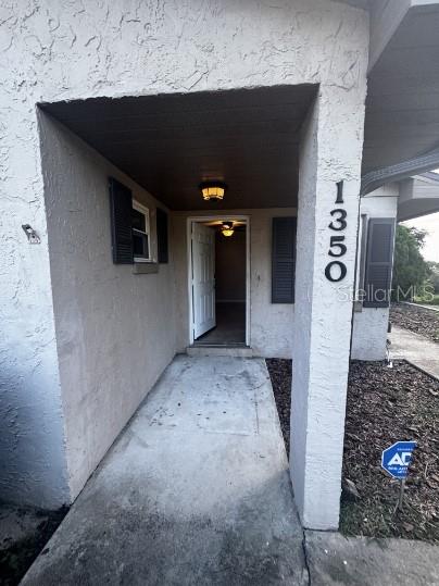 A covered concrete entryway leads to an open front door of a stucco house — 1340 ANDERSON STREET UNIT 1350, CLERMONT, FL