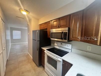 A kitchen features wood cabinets, stainless steel appliances, and light-colored countertops — 1340 ANDERSON STREET UNIT 1350, CLERMONT, FL