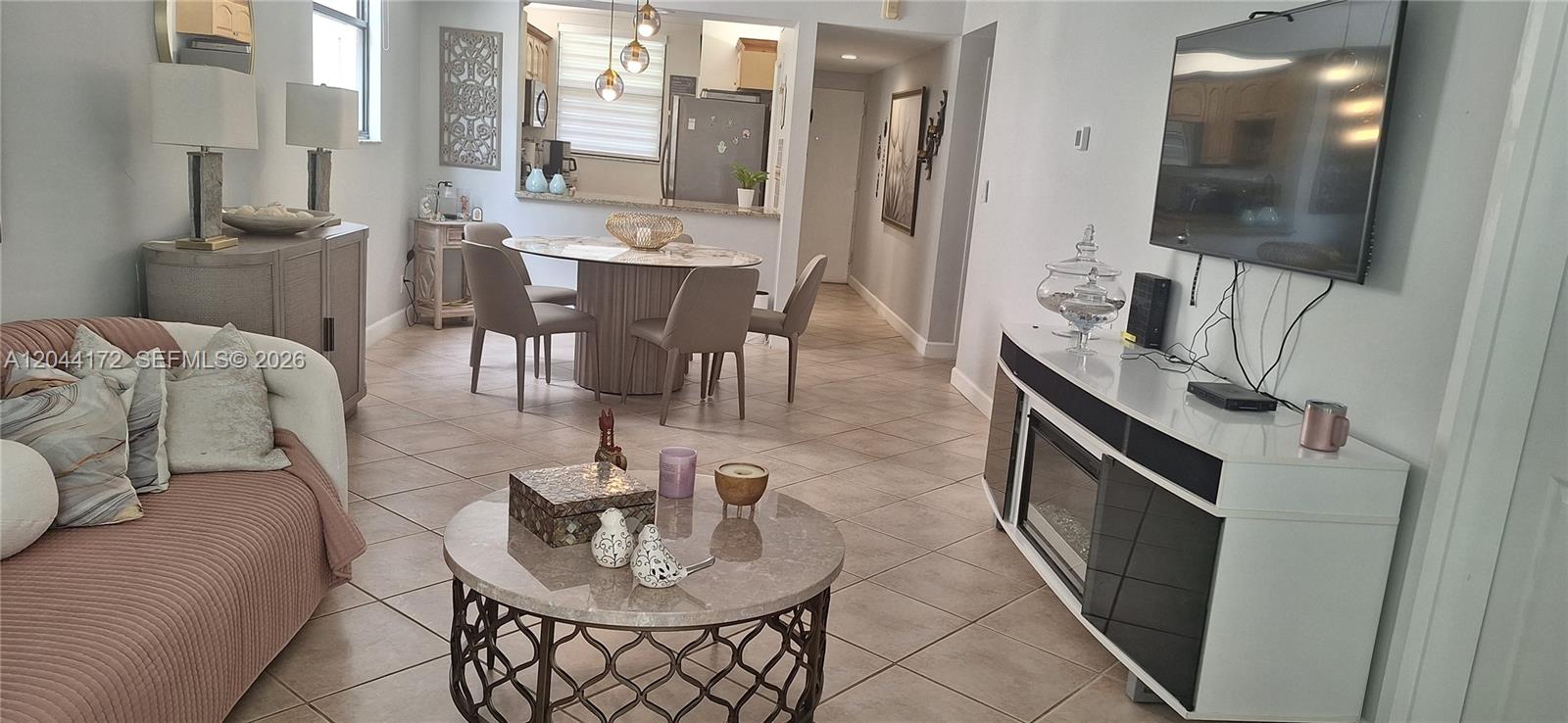 A living room and dining area feature tile flooring, a fireplace console, and neutral decor — CORAL SPRINGS, FL