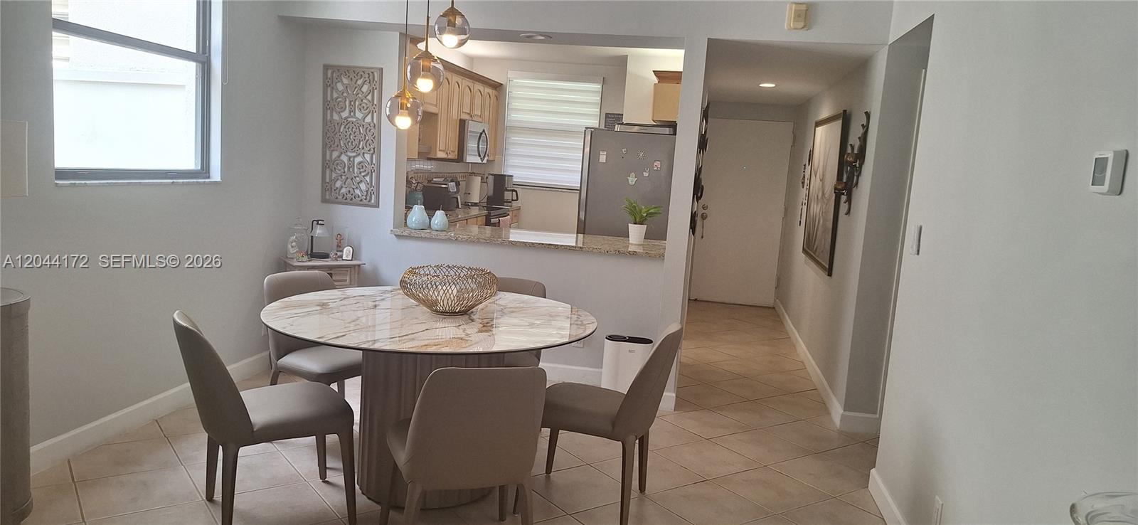 A dining area features a round marble table, four chairs, and a pass-through kitchen window — CORAL SPRINGS, FL
