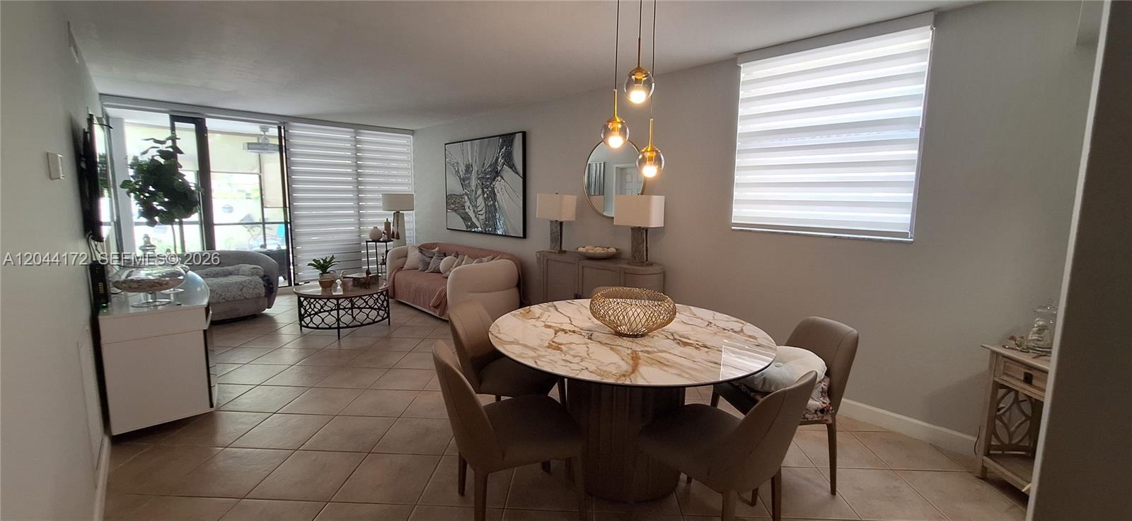 A dining area with a marble table sits in front of a living room space — CORAL SPRINGS, FL