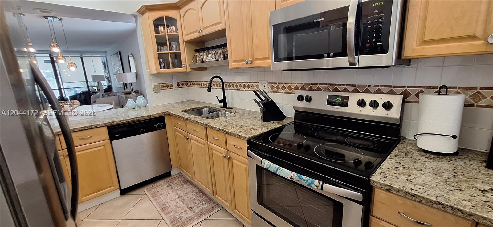 A kitchen with light wood cabinets, granite countertops, stainless steel appliances, and a tiled backsplash — CORAL SPRINGS, FL