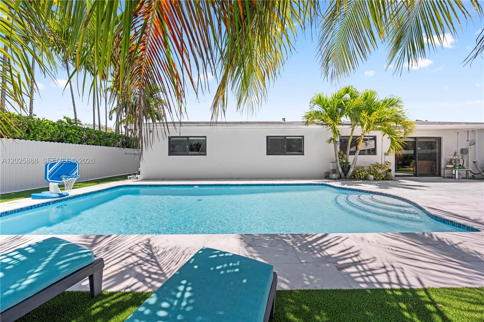 A backyard features a swimming pool, lounge chairs, palm trees, and a white house exterior — 12731 SW 47th Ter, Miami FL 33175, MIAMI, FL