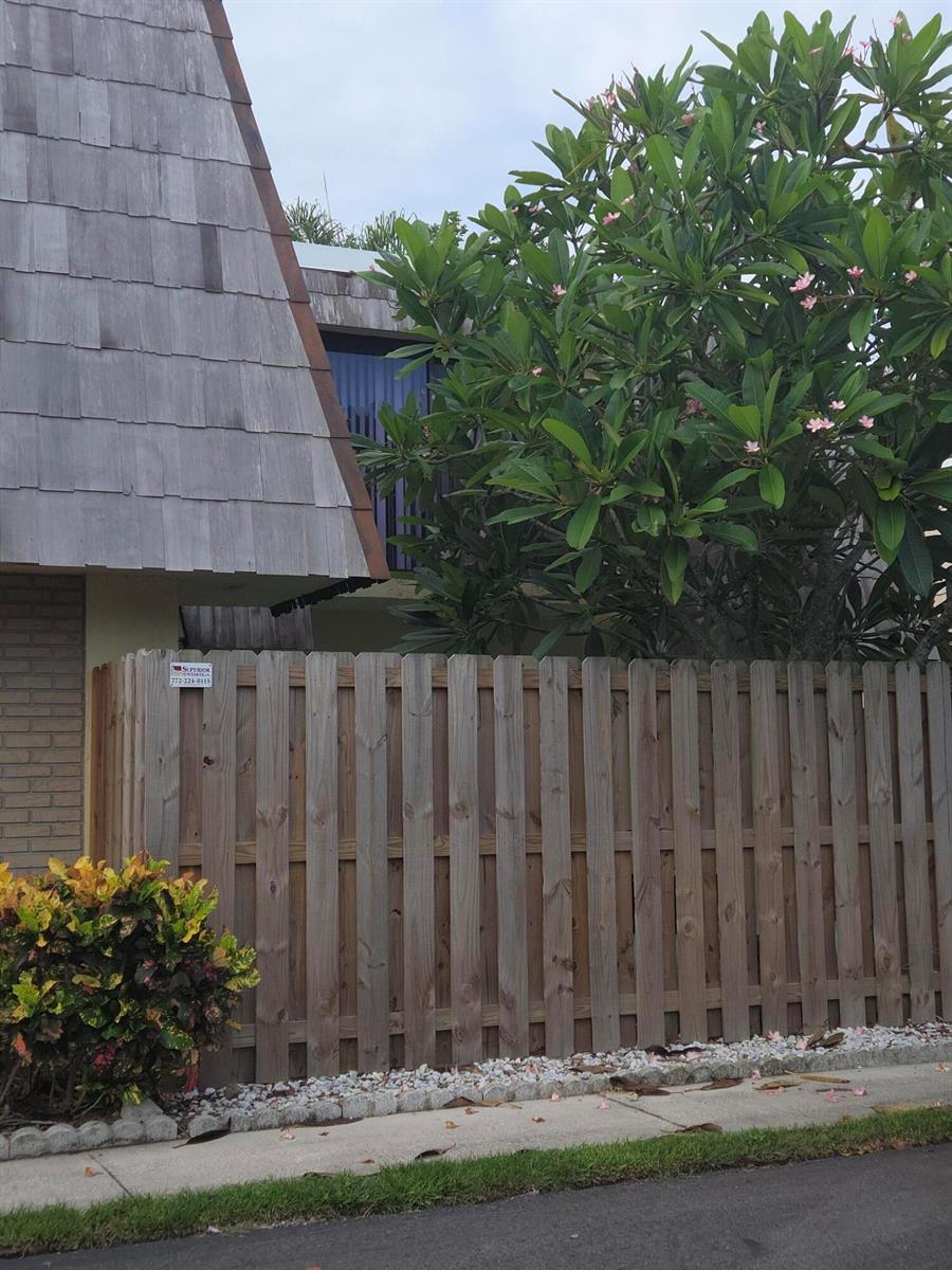 A wooden fence stands in front of a house with a steep, shingled roof — 1170 6th Avenue # 3a, Vero Beach FL 32960, VERO BEACH, FL