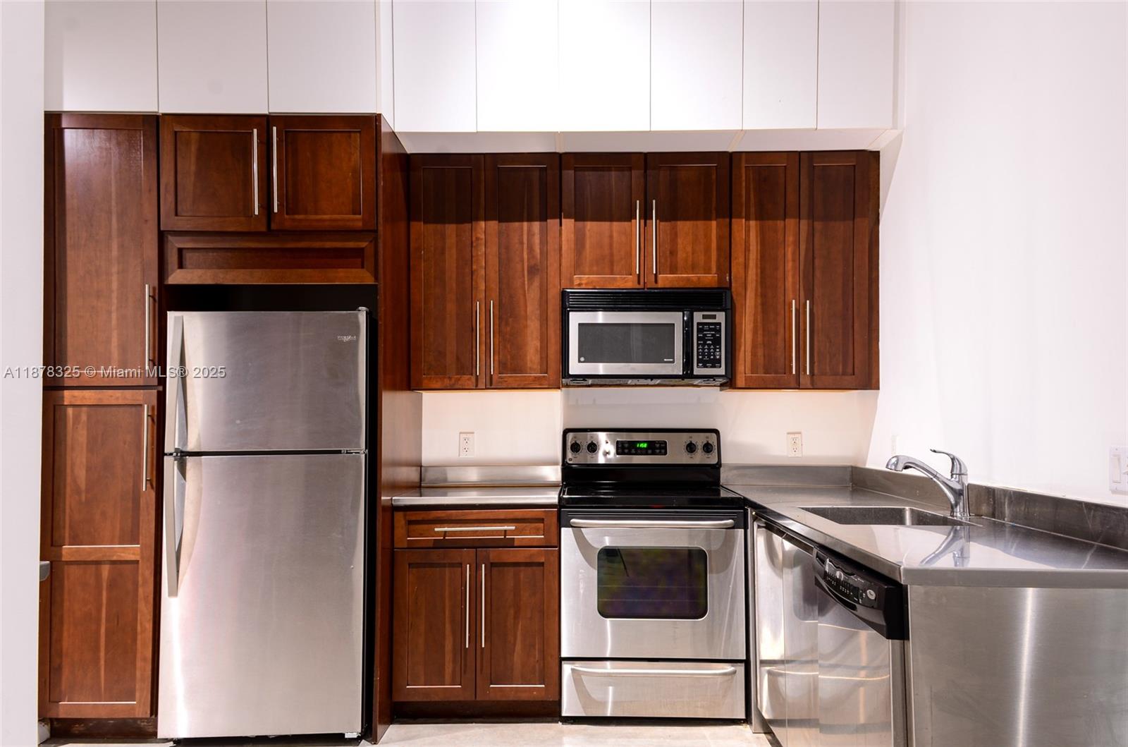 This kitchen features dark wood cabinets, stainless steel appliances, and a stainless steel countertop — 250 NW 23rd st # 308, Miami FL 33127, MIAMI, FL