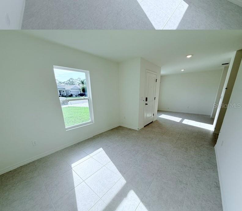 An empty room with light-colored tile flooring, a single window, and a white door — 32 KALAMAZOO TRAIL, PALM COAST, FL