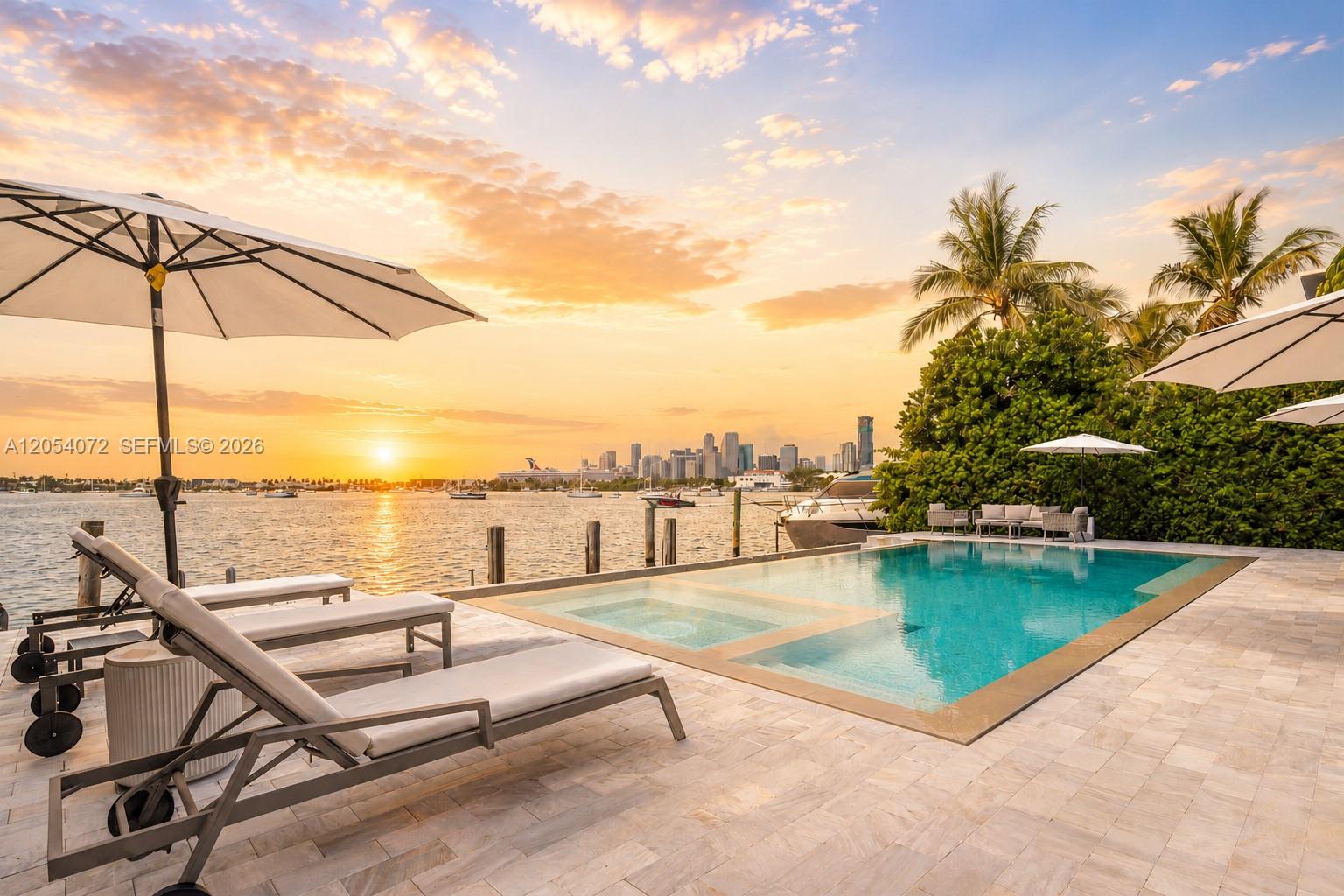 A swimming pool and lounge chairs overlook a bay with a distant city skyline — 1300 S Venetian Way, Miami FL 33139, MIAMI, FL