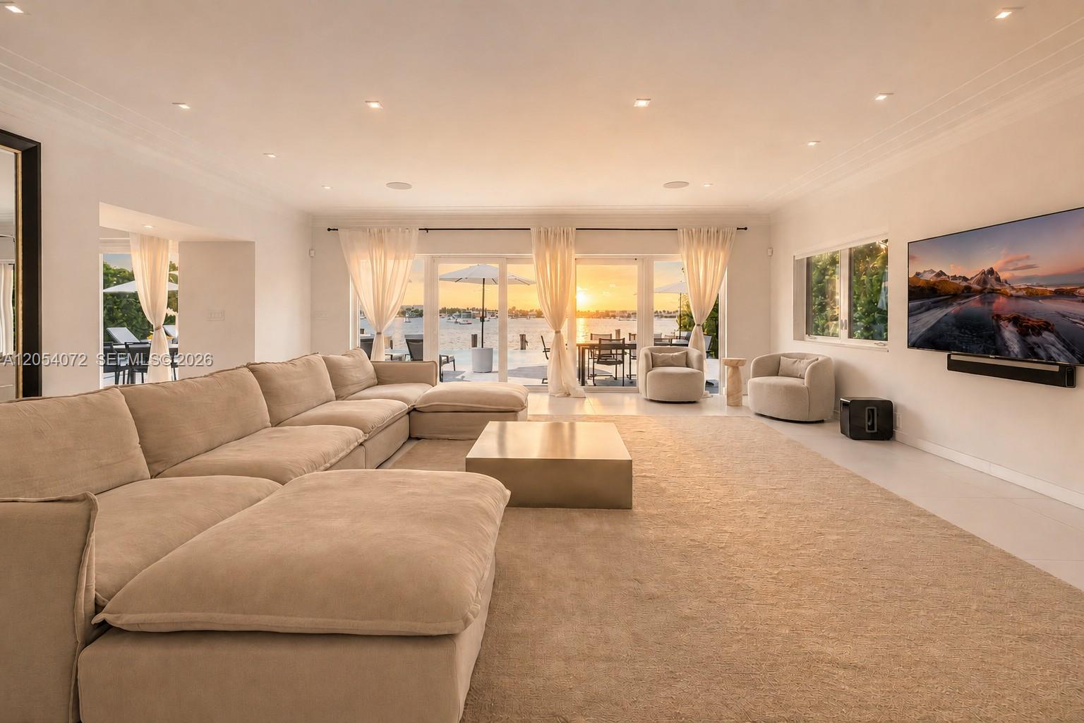 A spacious living room features a large sectional sofa, a metal coffee table, and waterfront views — 1300 S Venetian Way, Miami FL 33139, MIAMI, FL