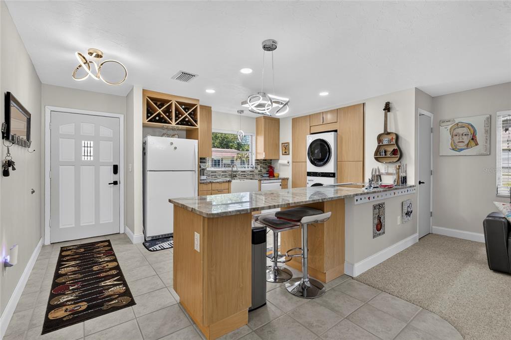 A kitchen features light wood cabinets, granite countertops, a breakfast bar, and a stacked laundry unit — 4549 TIPPECANOE TRAIL UNIT 20, SARASOTA, FL