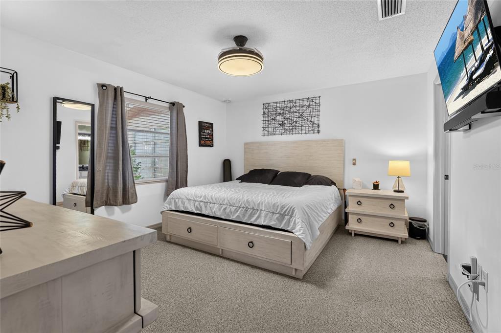 A bedroom features a light wood bed frame with storage, a matching nightstand, and carpeted flooring — 4549 TIPPECANOE TRAIL UNIT 20, SARASOTA, FL
