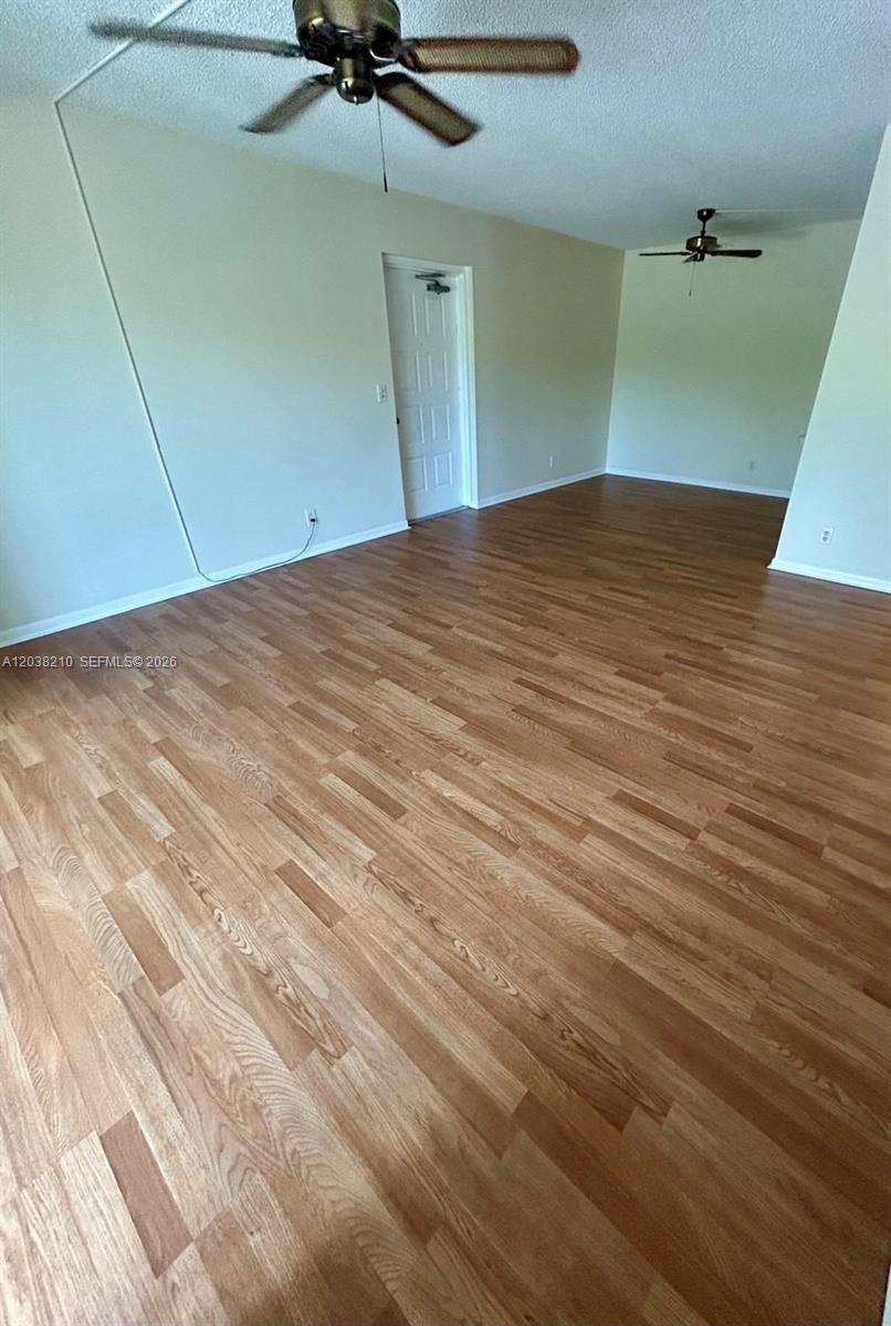 An empty room features light wood-look flooring, white walls, and two ceiling fans — 1113 Green Pine Blvd # H2, West Palm Beach FL 33409, WEST PALM BEACH, FL
