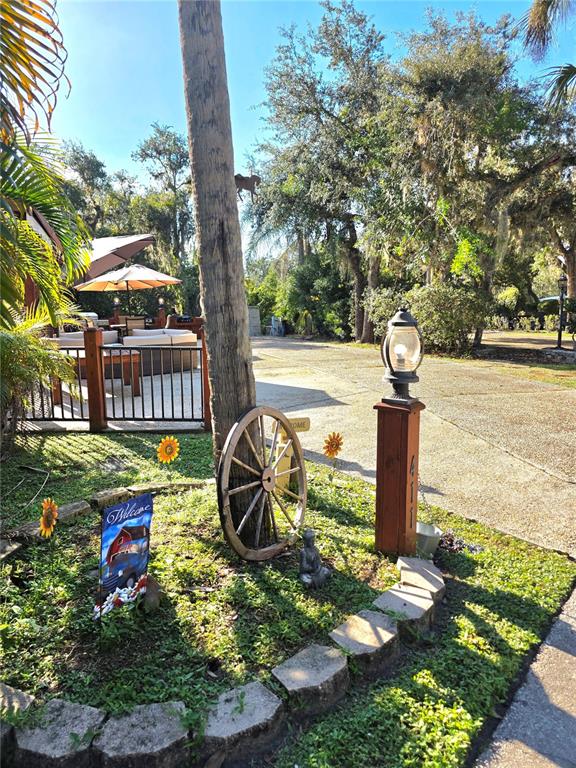 A wooden post with a lamp and house number stands beside a decorative wagon wheel — 411 LONGHORN DRIVE, LAKE WALES, FL