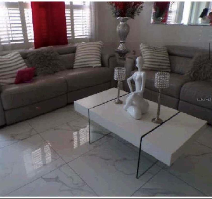 A living room features gray leather sofas, a white coffee table, and tiled flooring — 3107 W OSBORNE AVENUE, TAMPA, FL