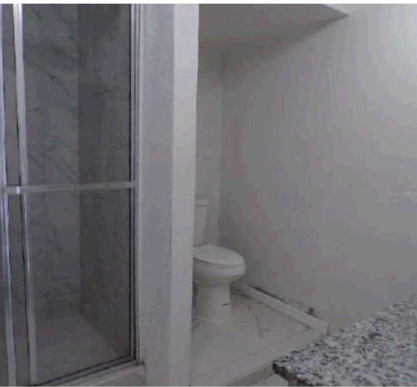 A bathroom features a glass-enclosed shower next to a toilet on a tiled floor — 3107 W OSBORNE AVENUE, TAMPA, FL