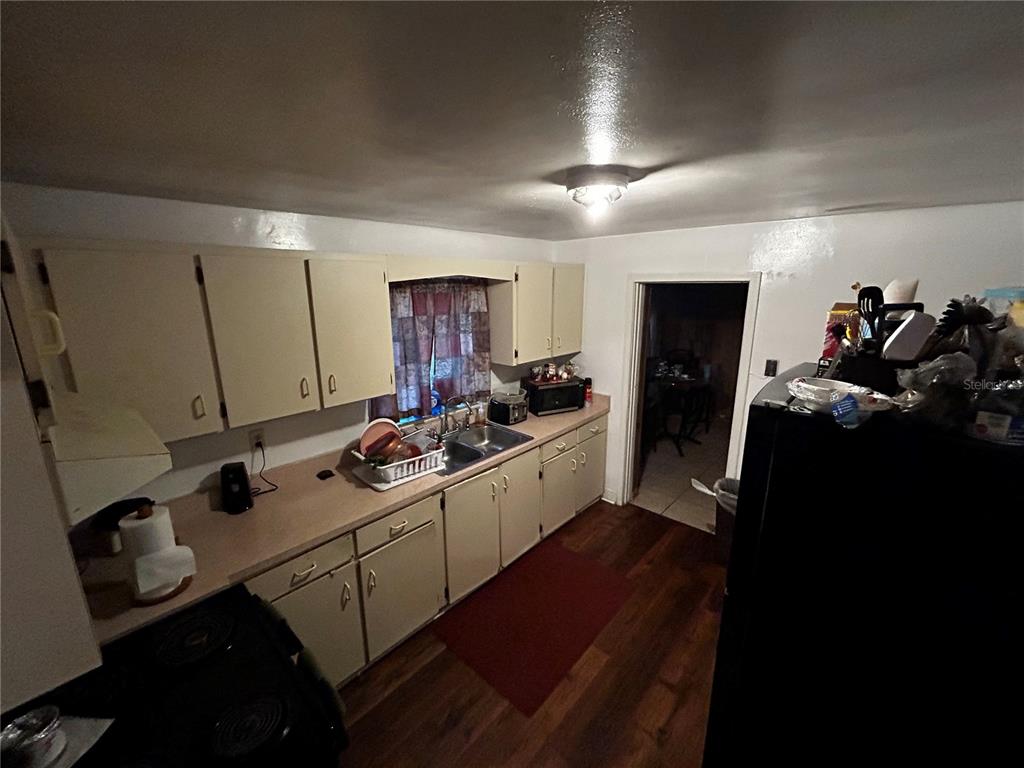 A kitchen features light-colored cabinets, laminate countertops, a double-basin sink, and dark wood-look flooring — 415 MODEL STREET, DAYTONA BEACH, FL