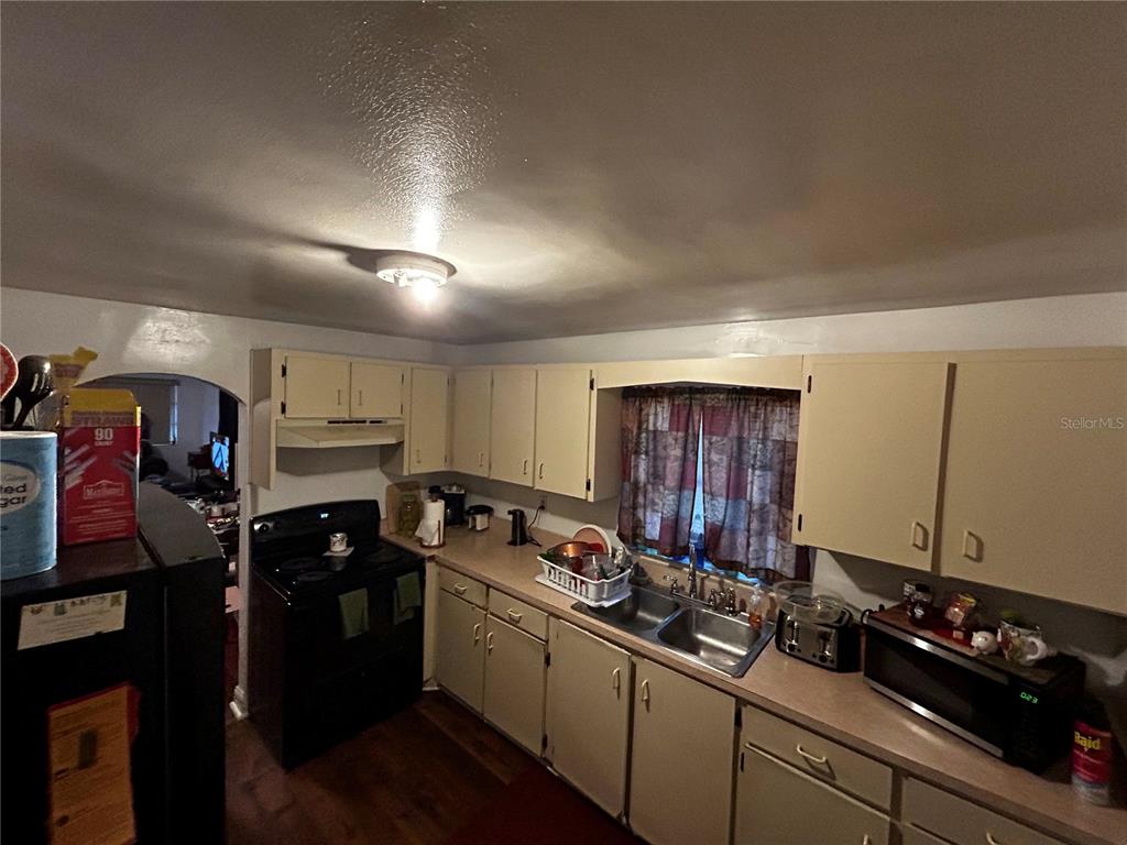 A kitchen features beige cabinets, laminate countertops, a double sink, and a black stove — 415 MODEL STREET, DAYTONA BEACH, FL