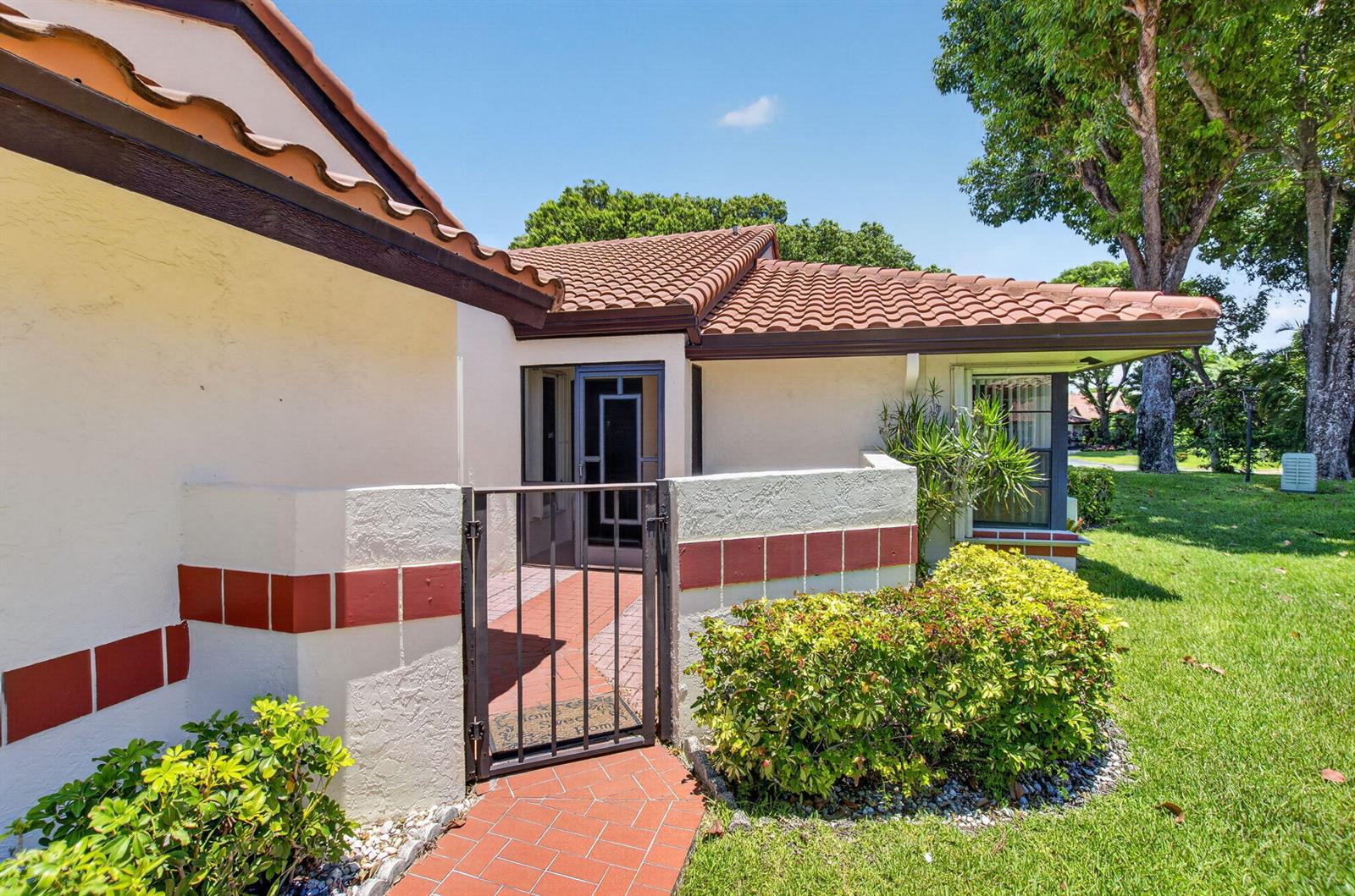 A gated courtyard entrance leads to a home with a tiled roof and stucco walls — 10546 Beach Palm Court # B, Boynton Beach FL 33437, BOYNTON BEACH, FL