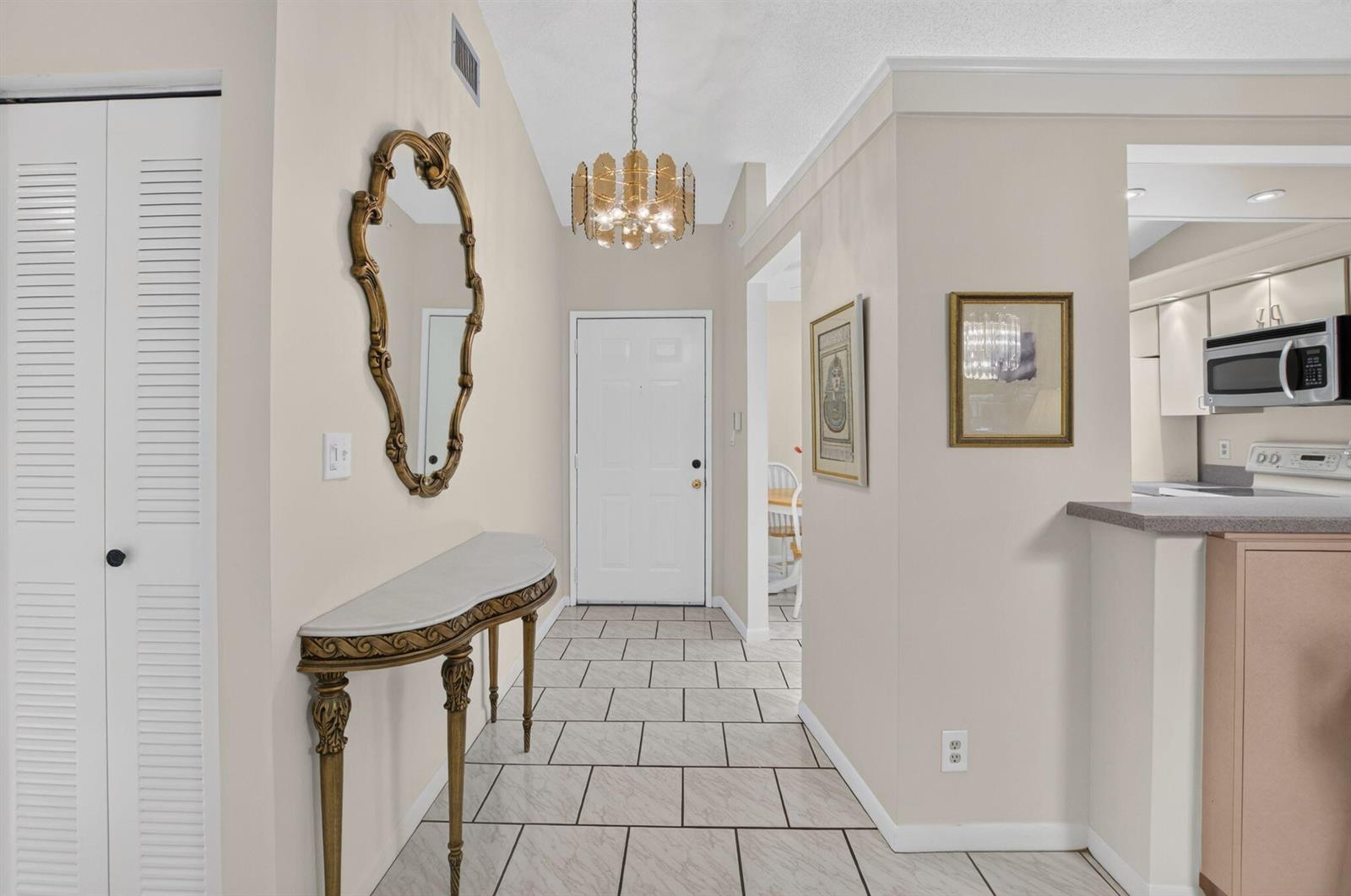 A tiled entryway features a gold-framed mirror, a console table, and a hanging light fixture — 10546 Beach Palm Court # B, Boynton Beach FL 33437, BOYNTON BEACH, FL