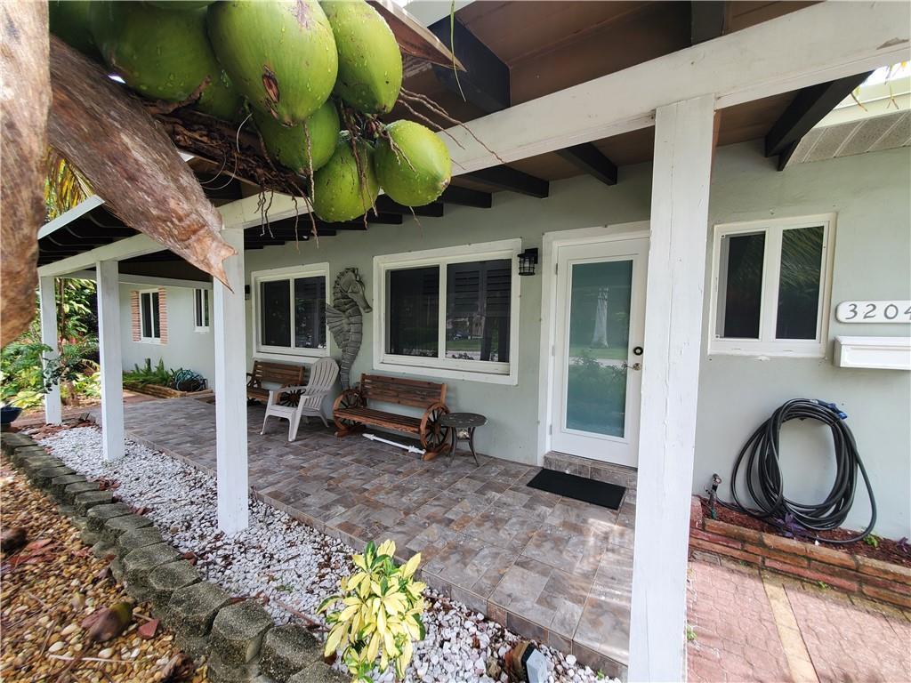 A covered porch features tiled flooring, wooden benches, and a cluster of coconuts overhead — 3204 NE 6th Street, Pompano Beach FL 33062, POMPANO BEACH, FL