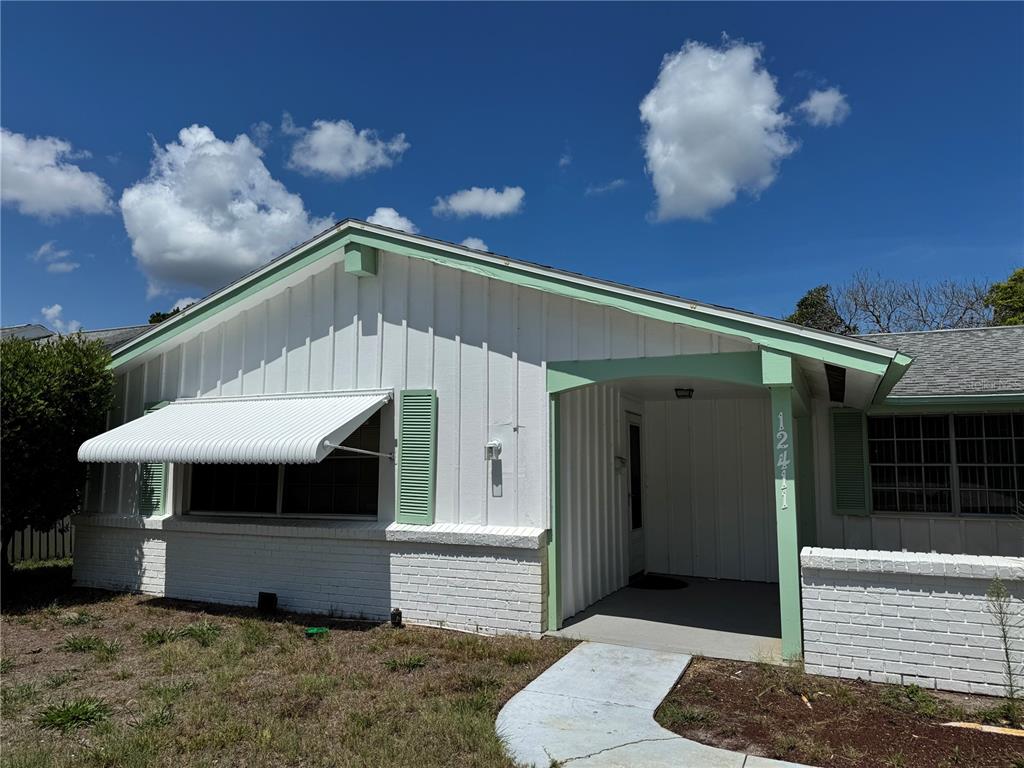 A single-story house with white vertical siding, brick accents, and light green trim — 12411 PARTRIDGE HILL ROW, HUDSON, FL