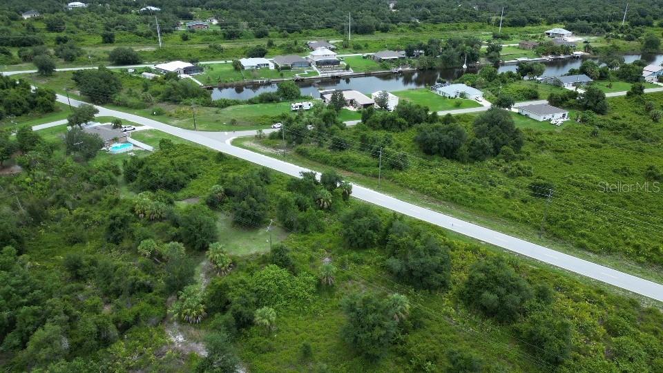 An aerial view shows a paved road running through a rural area with scattered houses — 1433 SULSTONE DRIVE, PUNTA GORDA, FL