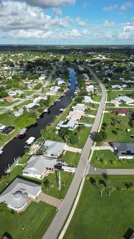 An aerial view shows a residential neighborhood with houses lining a canal and street — 1433 SULSTONE DRIVE, PUNTA GORDA, FL