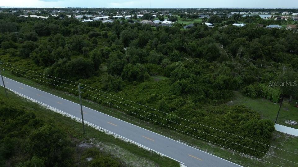 An aerial view shows a vacant, wooded lot adjacent to a paved road — 1433 SULSTONE DRIVE, PUNTA GORDA, FL