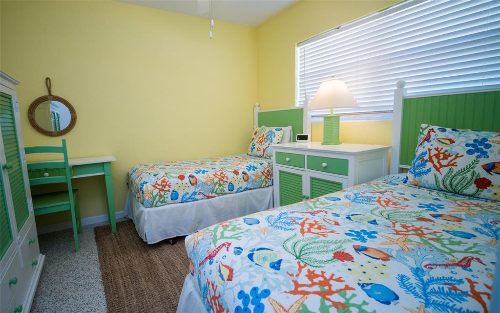 A bedroom with two twin beds, yellow walls, green furniture, and colorful coral-patterned bedding — 1312 66TH STREET NW, BRADENTON, FL
