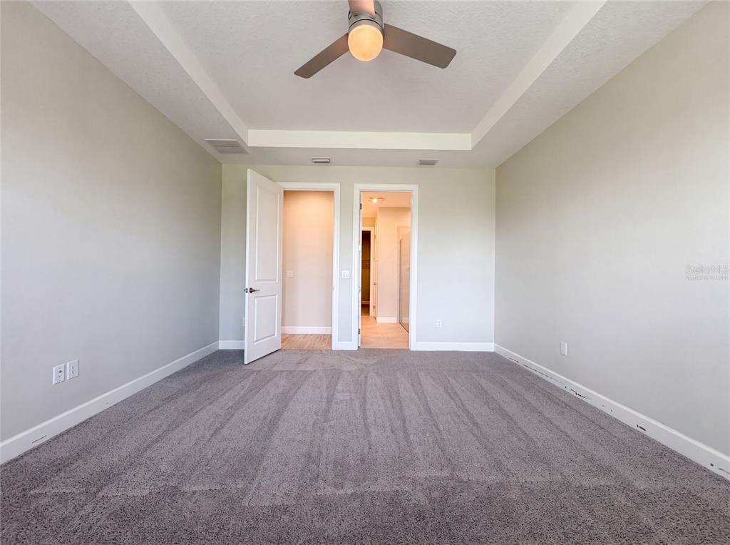 A carpeted bedroom features a tray ceiling with a fan and two doorways — 4516 CRESTPOINT WAY, PALMETTO, FL