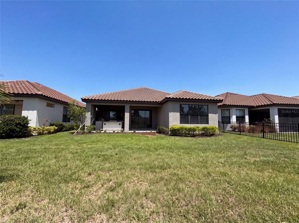 The rear exterior of a single-story house with a covered patio and a fenced yard — 4516 CRESTPOINT WAY, PALMETTO, FL