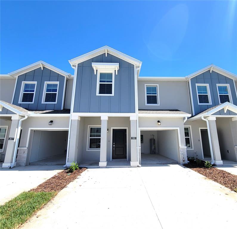 The exterior of a multi-unit townhouse features blue siding, white trim, and open garages — 2881 PIERR STREET, DAVENPORT, FL