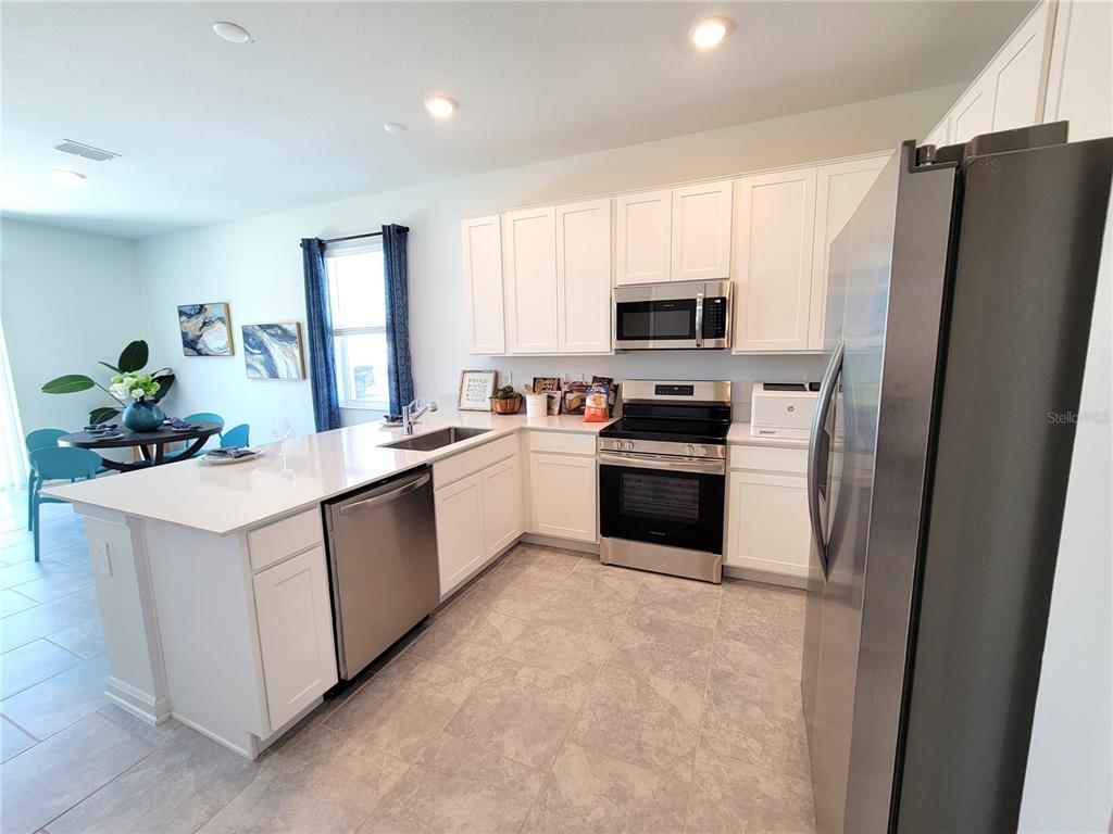 A modern kitchen features white cabinets, stainless steel appliances, and a large quartz island — 2881 PIERR STREET, DAVENPORT, FL