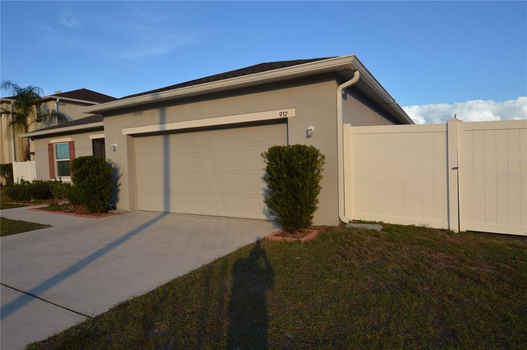 A gray house with a two-car garage and a white vinyl privacy fence — 937 GILA PLACE, KISSIMMEE, FL