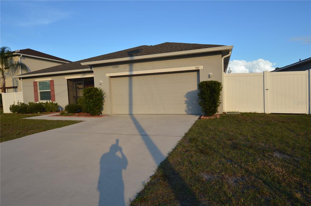 A single-story house with a gray exterior, a two-car garage, and a white privacy fence — 937 GILA PLACE, KISSIMMEE, FL