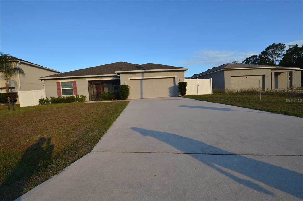 A single-story house with a two-car garage and a concrete driveway under a clear sky — 937 GILA PLACE, KISSIMMEE, FL