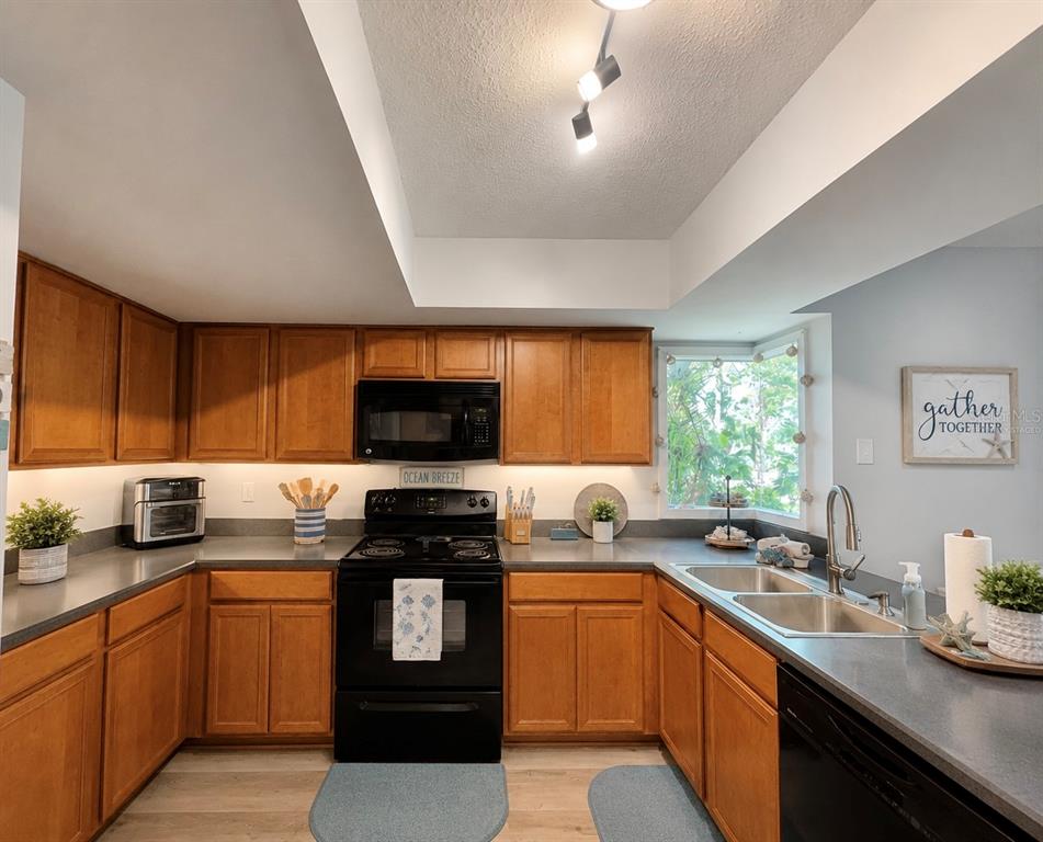 A kitchen with wood cabinets, black appliances, gray countertops, and a window over the sink — 6 MASTERS COURT UNIT 6, PALM COAST, FL