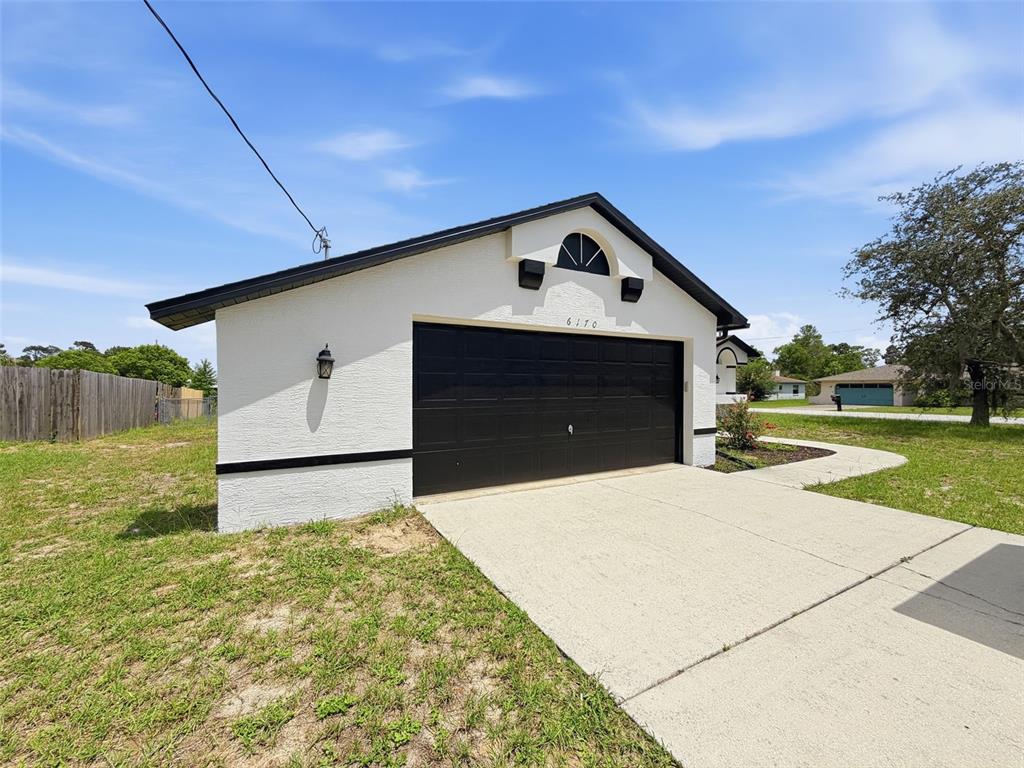 A white detached garage with a black door and trim sits on a grassy lot — 6170 GAINSBORO AVENUE, SPRING HILL, FL
