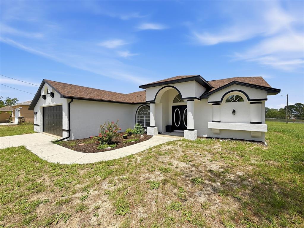 A single-story house with white stucco walls, a dark roof, and a front entryway arch — 6170 GAINSBORO AVENUE, SPRING HILL, FL