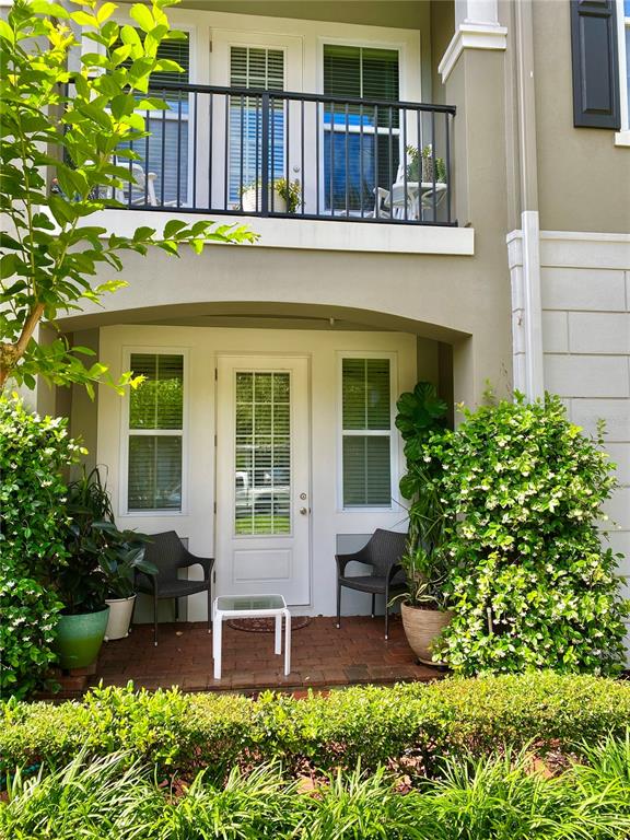 A two-story building exterior features a balcony above a patio with chairs and a table — 525 LANARK COURT, ORLANDO, FL