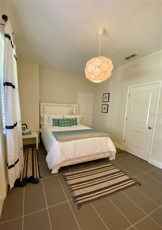 A bedroom features a bed with white bedding, a pendant light, and tiled flooring — 525 LANARK COURT, ORLANDO, FL