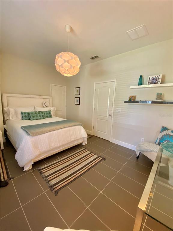 A bedroom features a white bed, a pendant light, tiled floors, and wall-mounted shelving — 525 LANARK COURT, ORLANDO, FL
