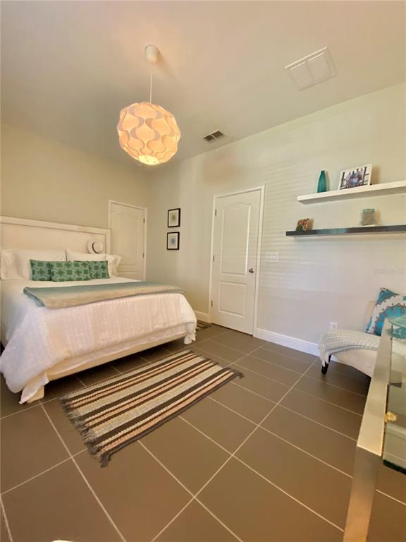 A bedroom features a bed, a pendant light, tiled floors, and wall-mounted shelves — 525 LANARK COURT, ORLANDO, FL
