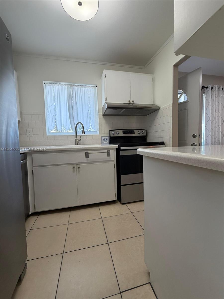 A kitchen features white cabinets, a stainless steel stove, and light-colored tile flooring — 1832 Sunny Drive # 32, Bradenton FL 34207, BRADENTON, FL