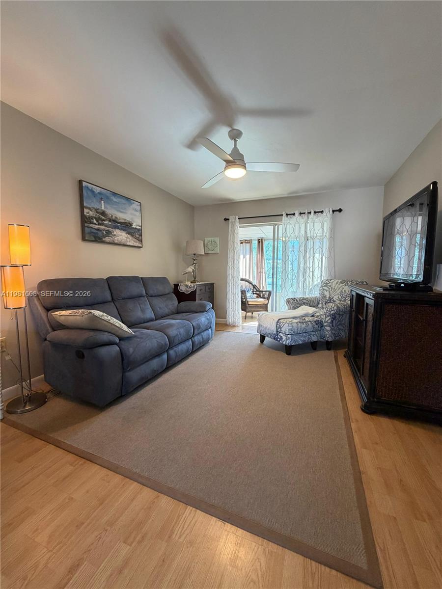 A living room features a blue sofa, patterned armchair, television console, and a ceiling fan — 1832 Sunny Drive # 32, Bradenton FL 34207, BRADENTON, FL