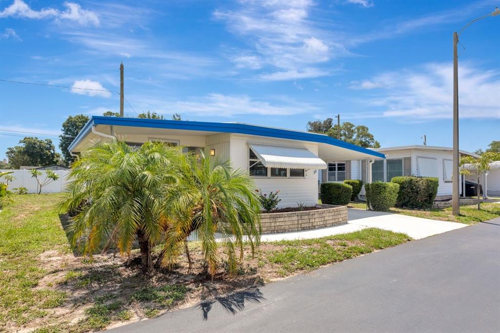 A single-story mobile home with a blue roof, white siding, and a palm tree out front — 9900 ULMERTON ROAD UNIT 35, LARGO, FL