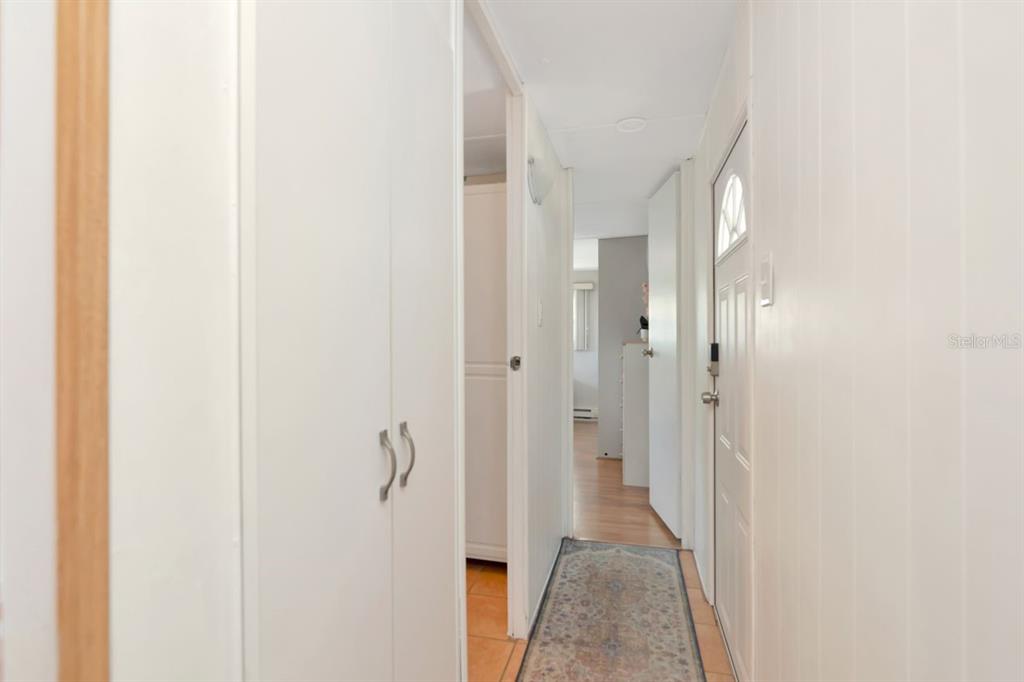 A narrow hallway features white walls, a tiled floor with a runner, and closed doors — 9900 ULMERTON ROAD UNIT 35, LARGO, FL